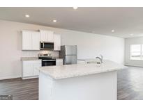 Modern kitchen with white cabinets, stainless steel appliances, and granite countertops at 243 Oliver Dr, Locust Grove, GA 30248
