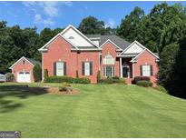 Charming brick home with a well-manicured lawn, lush greenery, and a detached garage on a sunny day at 4119 Alayna Lee Cir, Mcdonough, GA 30252
