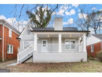 Charming grey brick home featuring a covered front porch with white railings and supporting columns at 1030 Westmoor Nw Dr, Atlanta, GA 30314