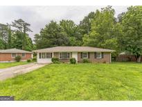 Charming single-story brick home with a well-maintained lawn and inviting curb appeal, shaded by mature trees at 1350 Lori Ct, Conley, GA 30288