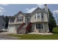 Charming two-story home boasts a well-maintained lawn, front-facing garage, and inviting front porch with decorative door and windows at 650 Flippen Rd, Stockbridge, GA 30281