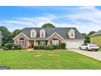 Charming single-Gathering home with stone accents, manicured lawn, dormer windows, and attached garage in a suburban neighborhood at 115 Glen Echo Dr., Covington, GA 30016