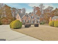 Stately brick two-story home with manicured lawn, mature trees and black shutters, perfect for a growing Gathering at 355 Woodbyne Dr, Fayetteville, GA 30214