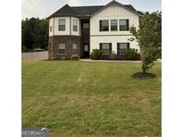Charming two-story home features a manicured lawn and classic design with a brick and white facade and black shutters at 175 Bridgemill Dr, Covington, GA 30014