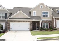 Charming townhome features a two-car garage, stone accents, and a well-manicured front lawn at 2845 Long Shadow Ct, Snellville, GA 30078