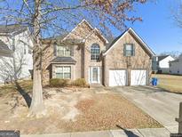 Charming two-story brick home with a two-car garage and a well-manicured front lawn on a sunny day at 4466 Estate St, South Fulton, GA 30349