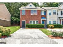 Charming red brick townhouse featuring a well-maintained front yard and a private driveway at 4862 Park Cir, Atlanta, GA 30349