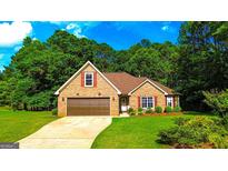 Charming brick home featuring an attached garage, manicured lawn, and mature trees in a desirable neighborhood at 6830 Peeksville Rd, Mcdonough, GA 30252