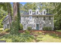 Stucco home with dormer windows and teal front door surrounded by mature landscaping and trees at 345 Kerrith Dr, Stockbridge, GA 30281