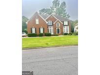 Elegant two-story brick home with a well-manicured lawn, black shutters and verdant landscaping at 12043 Olmstead Dr, Fayetteville, GA 30215