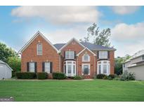 Beautiful two-story brick home with a well-manicured lawn and mature landscaping, offering great curb appeal at 12043 Olmstead Dr, Fayetteville, GA 30215