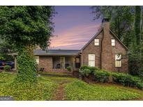Charming brick home featuring a covered porch and well-maintained landscaping with mature trees at 6230 S Summers Cir, Douglasville, GA 30135