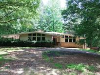 Inviting ranch home featuring mature trees, manicured bushes, and a charming American flag at 205 Avon Dr, Fayetteville, GA 30215