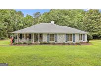 Charming single-story home featuring a well-manicured lawn and inviting front porch with American flag and brick accents at 107 Jennings Yard, Peachtree City, GA 30269