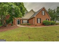 Charming brick home featuring a well-manicured lawn, mature trees, and a welcoming entrance at 1917 Kevin Se Dr, Conyers, GA 30013