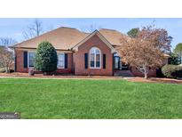 Charming single-story brick home featuring a manicured lawn and mature landscaping at 200 Magnolia Ct, Mcdonough, GA 30252