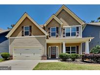 Charming two-story home showcasing a well-maintained lawn, a two-car garage, and a welcoming front porch area at 473 Cherry Creek Dr, Loganville, GA 30052