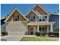 Charming two-story home featuring a welcoming front porch, attached garage, and manicured lawn at 473 Cherry Creek Dr, Loganville, GA 30052