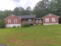 Charming one story red brick home with a covered porch and a large lawn at 390 Burg Rd, Locust Grove, GA 30248