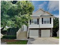 Inviting two-story home featuring a two-car garage and a charming stairway leading to the front door at 426 Summer Hill Cir, Stockbridge, GA 30281