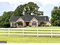 Charming brick home with a white picket fence and an American flag proudly displayed at 10 Wigwam Cir, Whitesburg, GA 30185