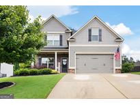 Charming two-story home featuring a well-manicured lawn, gray siding, brick accents and an attached two-car garage at 372 Cobblestone Trl, Dallas, GA 30157
