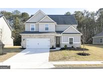 Charming two-story home featuring a brick and gray exterior, a two-car garage, and a well-manicured front yard at 3392 Arabian Farm Ln, Dacula, GA 30019