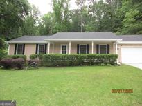 Charming single-story home with manicured lawn, trimmed bushes, and a welcoming front porch at 5848 Navarre Ct, Stone Mountain, GA 30087