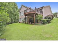 Expansive backyard featuring a spacious deck, lush lawn, and mature trees, perfect for outdoor entertaining at 133 Sea Island Dr, Peachtree City, GA 30269