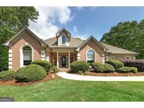 Charming brick home with manicured landscaping, pathway and arched windows at 715 Branchview Ct, Mcdonough, GA 30252