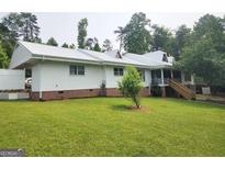Ranch home featuring a metal roof, brick accents, and a well-manicured lawn at 1470 Dunn Rd, Cumming, GA 30040