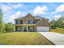 Inviting two-story brick home with a welcoming front porch, attached garage, and well-manicured lawn at 634 Gardner Rd, Stockbridge, GA 30281