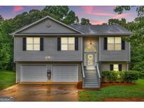 Charming two-story home features a two-car garage and a welcoming entrance with steps leading to the front door at 240 Mountain Ln, Covington, GA 30016