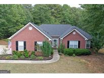 Charming brick home featuring a well-manicured lawn, lush landscaping, and a welcoming front entrance at 1129 River Green Ct, Mcdonough, GA 30252