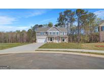 Charming two-story home boasts a landscaped yard, attached two-car garage, and traditional architectural details at 221 Ruthe Cv, Locust Grove, GA 30248