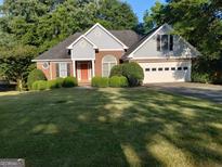 Charming single Gathering home with a well-manicured lawn, brick facade, and two-car garage at 35 Knollwood Pl, Covington, GA 30014