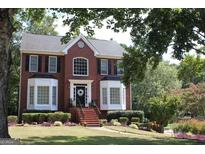 Charming red brick two-story home with a well-manicured lawn and nicely landscaped flower beds at 9342 Carillon Ct, Jonesboro, GA 30236
