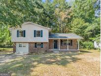 Charming two-story home with brick and siding exterior, complemented by a cozy front porch and lush greenery at 6505 Cedar Hurst Trl, South Fulton, GA 30349