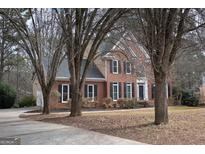 Brick two-story home featuring black shutters, mature trees, and well-maintained landscaping at 155 Glenwood Ln, Fayetteville, GA 30215