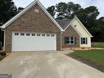 Charming brick and siding home featuring a two-car garage and well-maintained front yard at 521 Deadwood Trl, Locust Grove, GA 30248