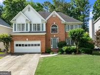 Charming two-story brick home with lush green lawn, attached garage and mature trees at 1504 Oglethorpe Dr, Suwanee, GA 30024