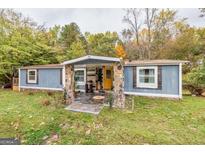 Charming single story home featuring wood facade, stone pillars, yellow door, and a cozy covered porch at 7138 Rockland Rd, Lithonia, GA 30038