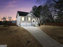 Two-story home featuring a well-manicured lawn and a two-car garage at dusk at 8870 Dornoch Cir, Winston, GA 30187