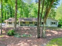 Charming single-story home with neutral siding and dark shutters, surrounded by mature trees at 1379 Branchwood Dr, Snellville, GA 30078