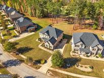 Expansive aerial view of a brick home with a lush lawn backing onto a wooded area in a desirable neighborhood at 6857 Louis Dr, Locust Grove, GA 30248