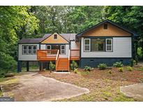 Charming home exterior featuring a deck, wooden stairs, and a well-maintained yard surrounded by lush trees at 243 Howell Sw Ter, Atlanta, GA 30331