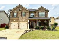 Traditional brick home featuring manicured lawn, covered entryway, and a two-car garage at 558 Hideaway Dr, Jonesboro, GA 30238