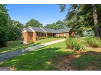 Beautiful brick home featuring manicured lawn, mature trees, and a paved driveway at 1000 Turner Church Rd, Mcdonough, GA 30252