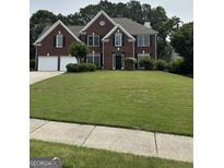 Elegant two-story brick home featuring a well-manicured lawn, two-car garage, and classic architectural details at 3381 Walkers Ridge Rd, Dacula, GA 30019
