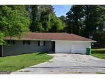 Ranch style home with brick facade, attached garage and mature trees in the front yard at 6286 Saddlewood Dr, Lithonia, GA 30058